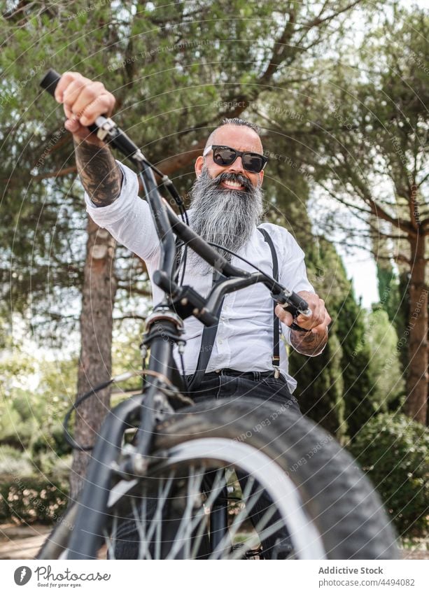 Bärtiger Hipster-Mann auf Fahrrad Stil formal Park Straße Lächeln Verkehr Glück Radfahrer froh Hobby trendy Vollbart Erwachsener Lebensmitte reif selbstbewusst