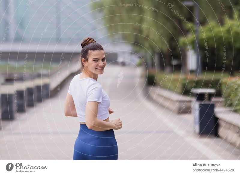 Junge Brünette Frau läuft auf Asphalt Straße im Sommer Park. Aktive sportliche kaukasische Frau hat Morgen Workout. Sportliche Person in Sportkleidung übt im Freien. Gekleidet Leggings und sportliche Top