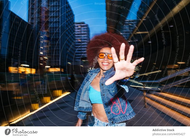 Stilvolle Frau mit Afrofrisur läuft zur Kamera Straße Afro-Look Mode Bekleidung Abend laufen sich[Akk] melden Gebäude Hand Outfit dunkel Dämmerung Haus