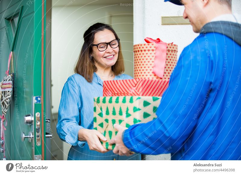 Zusteller bringt Weihnachtspakete. Frau zu Hause in der Tür stehend, empfängt Pakete für Weihnachtsgeschenke. Geschenk Weihnachten Versand Glück Lieferant