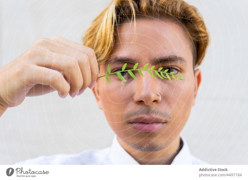 Hübscher Mann mit grünem Zweig Wand Pflanze Stil Flora Vegetation Straße Vorschein Kleidungsstück Gebäude Bekleidung Großstadt Starrer Blick gutaussehend