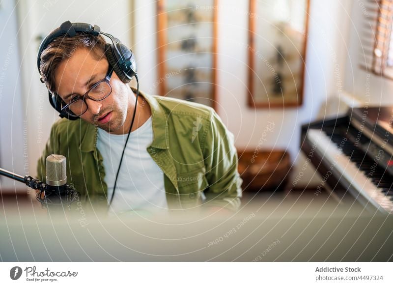 Mann mit Kopfhörern bei der Arbeit am Computer benutzend Arbeitsplatz Arbeitsbereich Konzentration professionell Atelier männlich Gerät Job Beruf Tisch Monitor