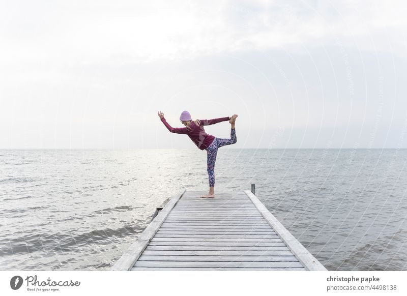 Frau in Sportbekleidung macht Yoga am Steg vor Meer Herbst See Fitness ufer Gesundheit Training sportlich Wellness Lifestyle Außenaufnahme Erwachsene Mensch