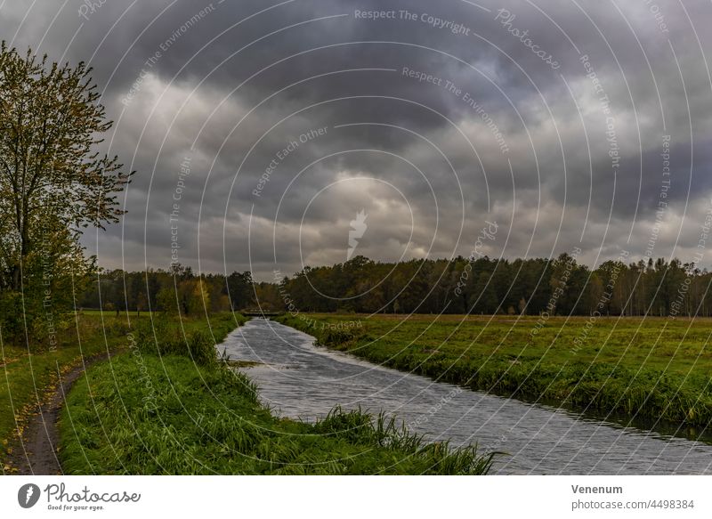 Sturm Hendrik, viele Wolken am Himmel über einer Wiese mit einem Fluss während des Sturms Flüsse Wasser Wasserreflexionen Wald Wälder Ast Niederlassungen