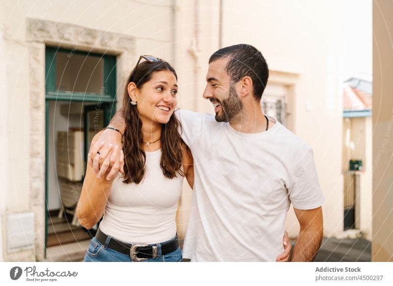 Fröhliches, liebendes ethnisches Paar lächelt, während sie die Straße hinuntergehen laufen Lachen Umarmung Liebe heiter Partnerschaft Zusammensein romantisch