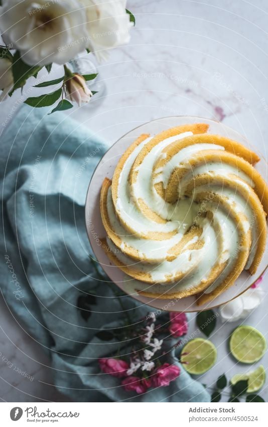 Limettenbiskuit auf Teller neben Blumen und Limettenscheiben Kuchen Kalk Schwamm Dessert Konditorei Zitrusfrüchte Biskuit gebacken geschmackvoll Frucht