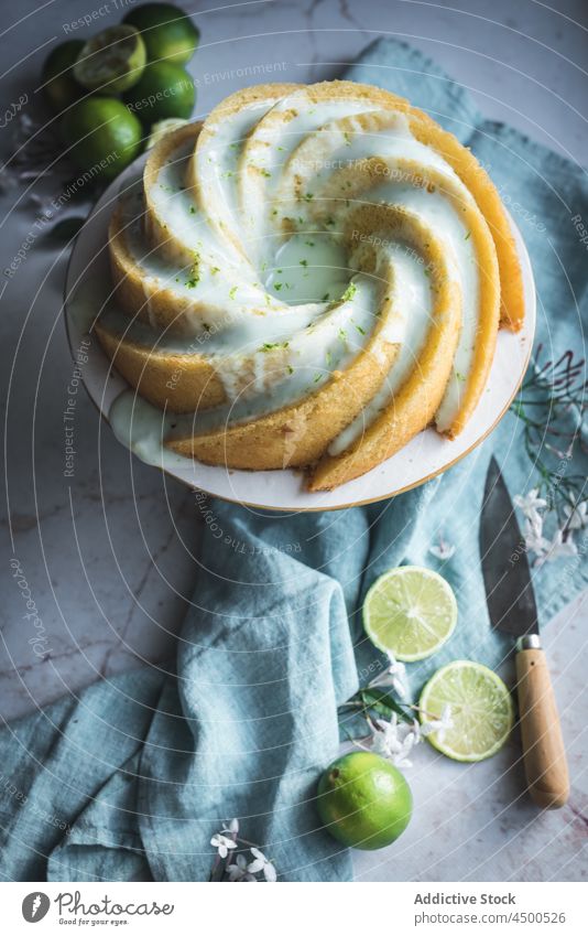 Limettenbiskuit auf Teller neben Blumen und Limettenscheiben Kuchen Kalk Schwamm Dessert Konditorei Zitrusfrüchte Biskuit gebacken geschmackvoll Frucht