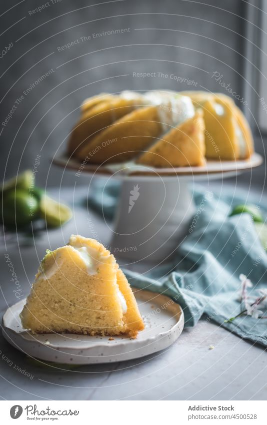 Limettenbiskuit auf Teller neben Blumen und Limettenscheiben Kuchen Kalk Schwamm Dessert Konditorei Zitrusfrüchte Biskuit gebacken geschmackvoll Frucht