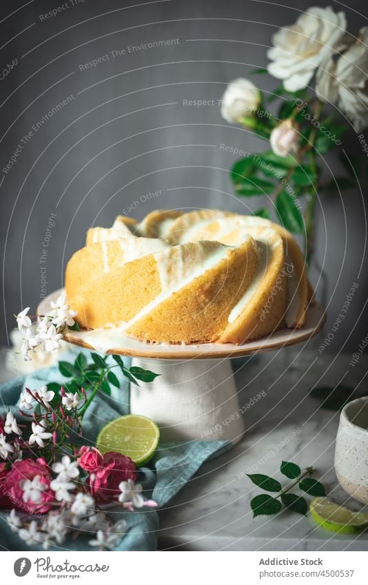 Limettenbiskuit auf Teller neben Blumen und Limettenscheiben Kuchen Kalk Schwamm Dessert Konditorei Zitrusfrüchte Biskuit gebacken geschmackvoll Frucht