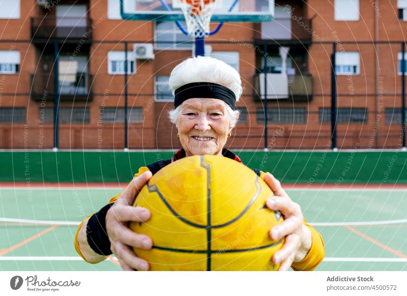 Fröhliche Seniorin mit Basketball auf dem Spielplatz Frau Ball spielen Sportpark Hobby Gesunder Lebensstil Training reif Lächeln heiter positiv Aktivität