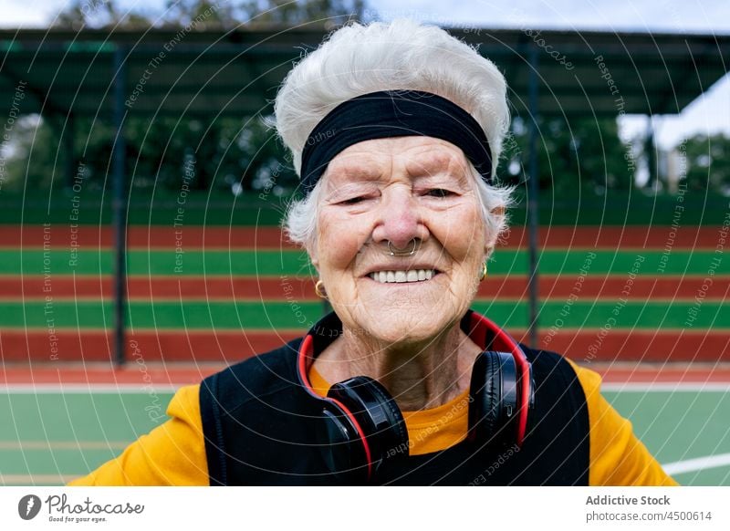 Glückliche Seniorin in Sportkleidung und Kopfhörern Frau meloman Sportpark Hobby Gesunder Lebensstil Musik auflehnen informell durchbohrt Training reif positiv