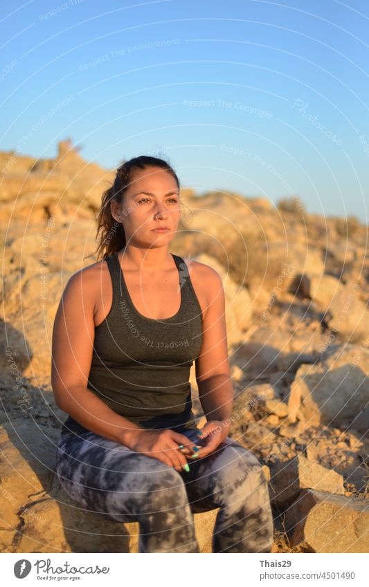 Eine junge Reisende Mädchen sitzen auf der Spitze des Berges in Negev-Wüste und genießen Sie die Schönheit der Natur. Junges Mädchen Liebe wildes Leben, Reisen, Freiheit. Ein Mädchen sitzt auf dem Rand der Klippe und Blick auf die Sonne