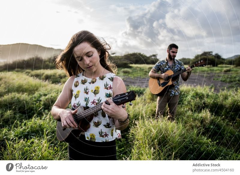 Freunde Musiker stehen im Feld und spielen Gitarre Frau Mann Ukulele Instrument Natur männlich akustisch Windstille lässig Konzentration Zusammensein