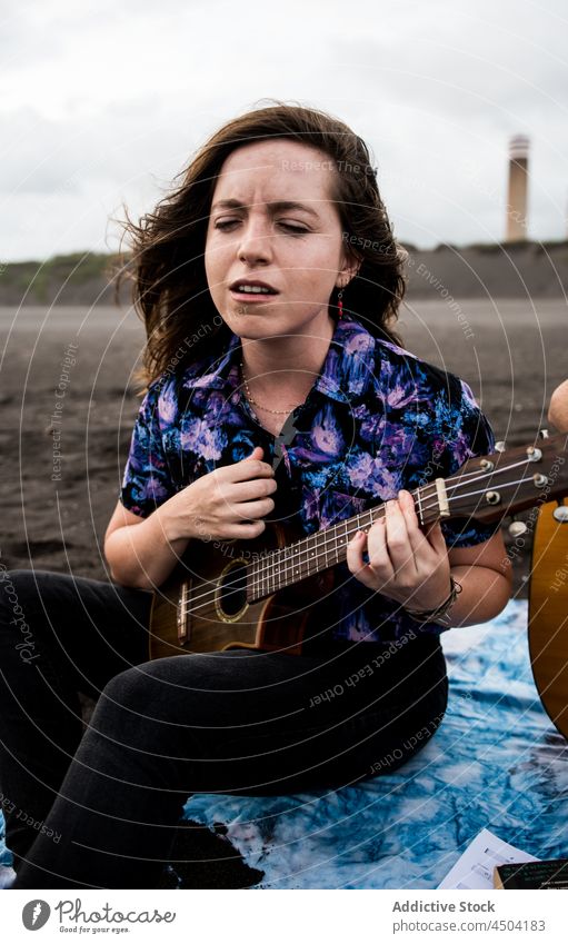 Musikerin spielt Ukulele am Meeresufer im Tageslicht Frau spielen Instrument Gesang Talent Strand singen Hobby Natur Melodie ausführen Sand genießen tagsüber