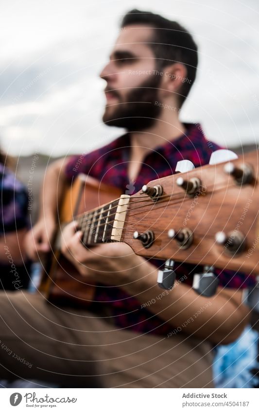 Mann Musiker spielt Gitarre am Meeresufer bei Tageslicht spielen akustisch Instrument Gesang Talent Strand singen Hobby Natur Melodie ausführen Sand genießen