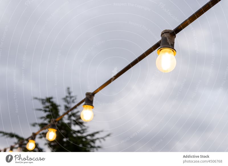 Hängende Glühbirnen unter einem bewölkten Himmel elektrisch Licht Linie im Freien Elektrizität Lampe Party Knolle wolkig erhängen Draht Abenddämmerung grau