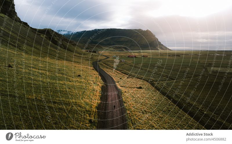 Straße durch ein Gebirgstal bei Sonnenuntergang Person Spaziergang Weg Hügel Berge u. Gebirge Natur Landschaft erkunden Reisender malerisch Berghang Wiese