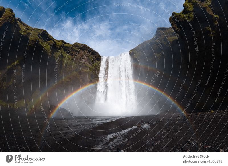 Mächtiger Wasserfall und Regenbogen in felsiger Schlucht Natur Klippe Kaskade Kraft platschen strömen Landschaft Energie malerisch reißend atemberaubend