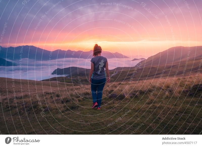 Anonyme Frau auf grasbewachsenem Hügel bei nebligem Wetter Tourist Berge u. Gebirge Nebel Abenteuer Natur Reise Sonnenuntergang Reittier Wanderer reisen