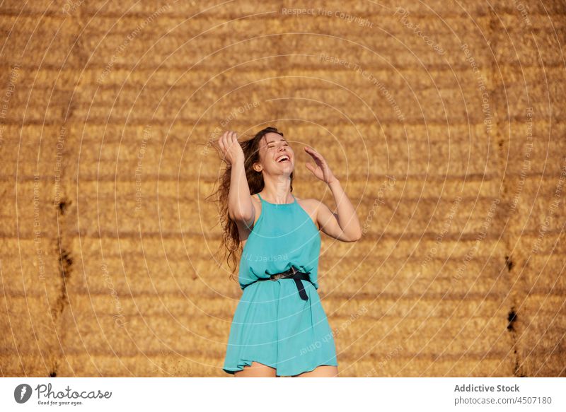 Lachende Frau mit fliegenden Haaren in der Nähe von Heuschobern Wind Haare kämmen Heugarben Spaß expressiv ländlich spielerisch Freude positiv froh heiter