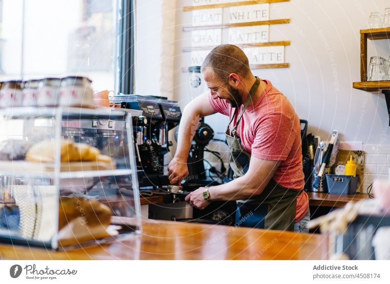 Barista macht Kaffee am Tresen Mann Kaffeehaus Kaffeemaschine Abfertigungsschalter brauen Portafilter Gerät Arbeit Personal Dienst professionell Kantine Schürze