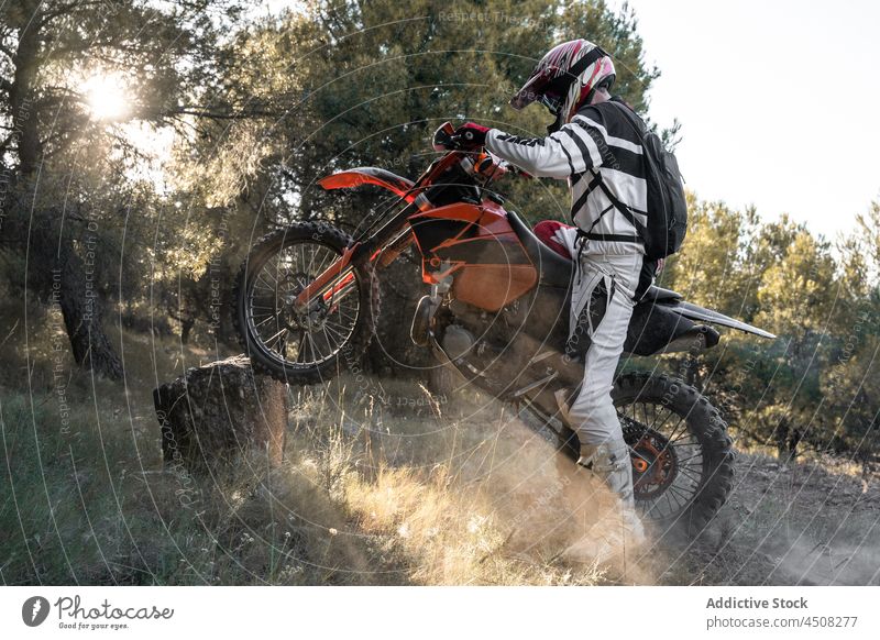 Unbekannter Motorradfahrer mit Motorrad auf Stein Mann extrem Fahrzeug Schutzhelm Sport Natur Waldgebiet Rennfahrer Langlauf männlich Verkehr Aktivität Baum