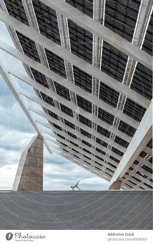 Unbekannte Frau macht Halbmond-Asana auf der Straße ardha chandrasana Yoga solar Panel Übung Training üben Energie beweglich Dame modern Sportbekleidung