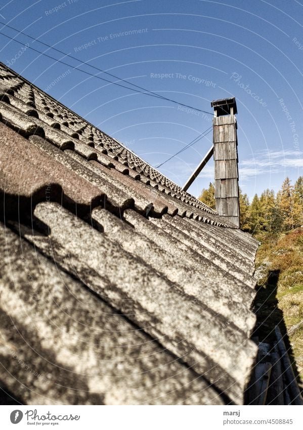 Aufrecht und stolz präsentiert sich dieser Kamin auf dem Dach einer Almhütte. Mit Lärchenschindeln und verzurrt vor Sturm und Wetter geschützt. verwittert alt