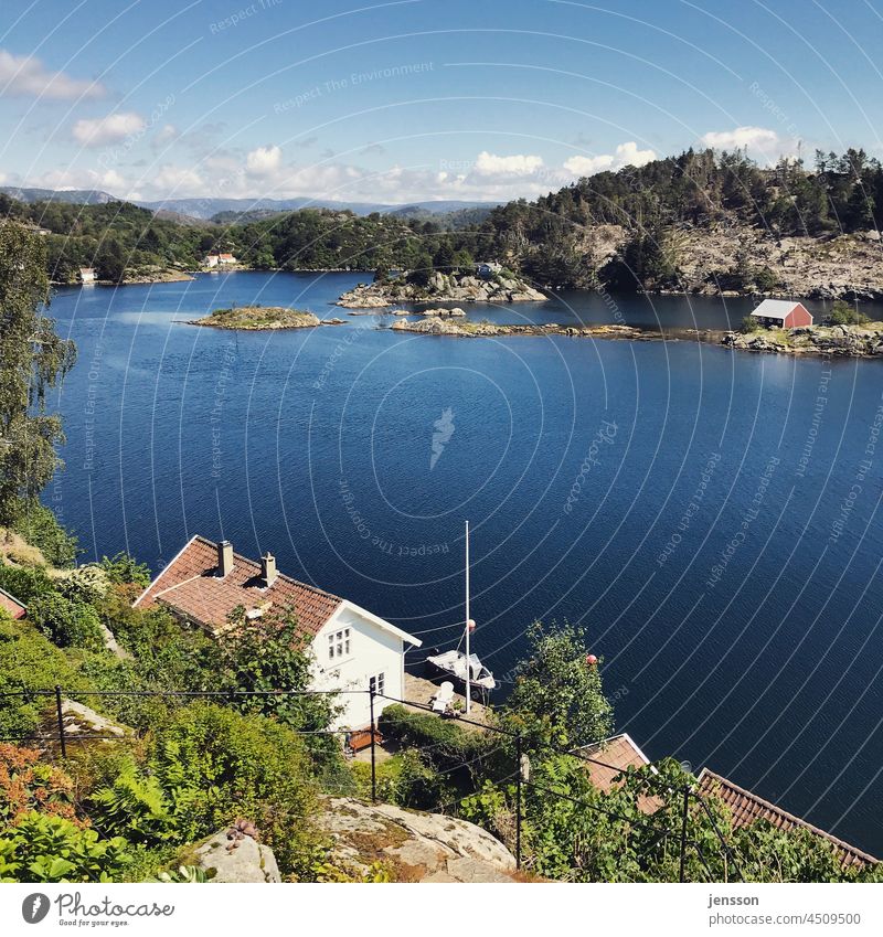 Weißes Holzhaus an einem norwegischen Fjord Norwegen Norwegenurlaub Küste Schärengarten Schäreninsel weiß blau Blauer Himmel Meer Meereslandschaft Wasser