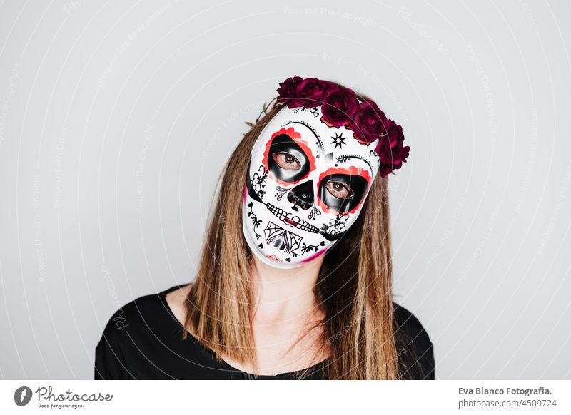 Frau trägt mexikanische Gesichtsmaske während Halloween-Feier. Frau trägt Skelett-Kostüm und rote Rosen Diadem auf dem Kopf. Halloween-Party-Konzept