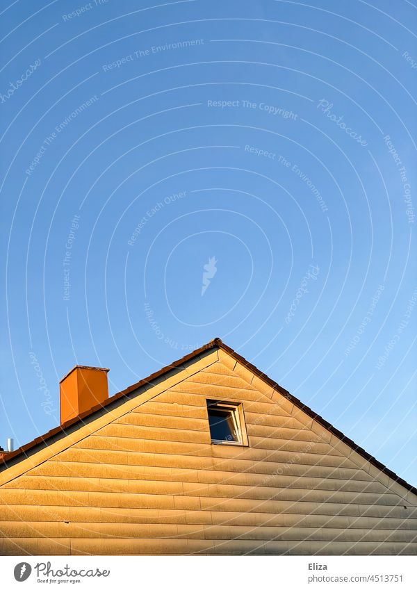 Von der Sonne beschienener Giebel eines Hauses vor blauem Himmel Dach Fenster blauer Himmel Gebäude Fassade Schornstein