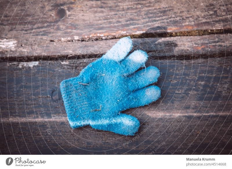 Handschuh auf einer Bank Handschuhe einzeln blau Menschenleer Außenaufnahme Farbfoto braun Licht Schatten Holzbrett Maserung Kontrast Strukturen & Formen