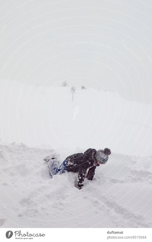 Kind spielt im Schnee auf Skipiste bei Nebel Wetter Tiefschnee Gipfel Winter Berge u. Gebirge Schneebedeckte Gipfel Alpen Landschaft kalt Spaß frieren