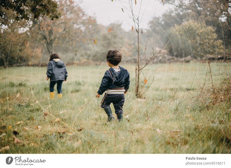 Bruder und Schwester spielen auf einer Wiese Geschwister Familie & Verwandtschaft Kind Kindheit Rückansicht 1-3 Jahre Herbst Gummistiefel Kinderspiel Lifestyle