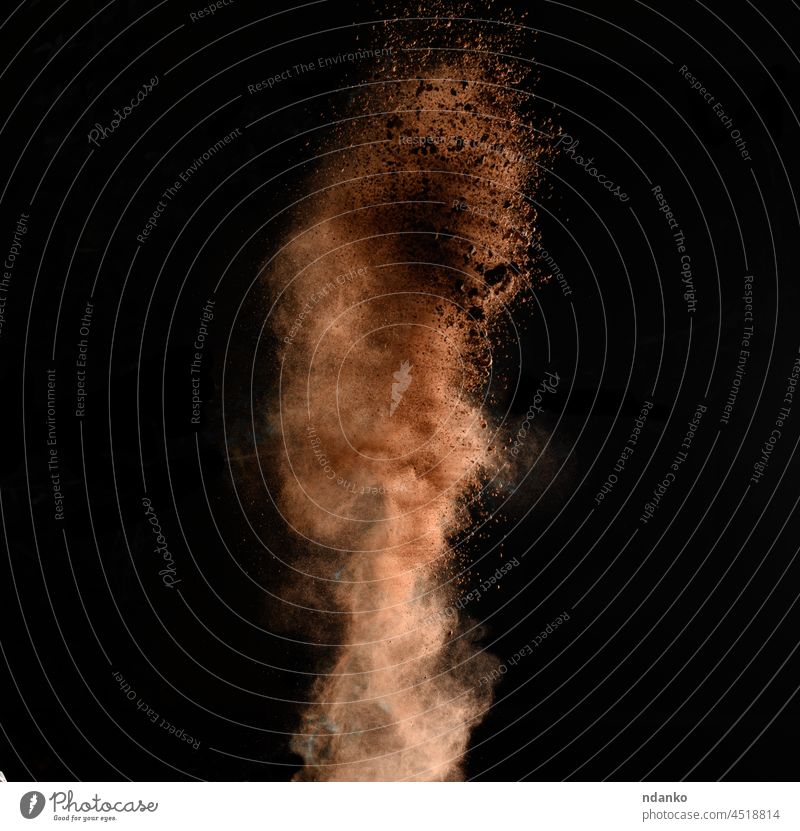 fliegende braune Kakaopartikel auf schwarzem Hintergrund. Puder fliegt auf Pulver Textur Schokolade Lebensmittel dunkel Staubwischen süß Explosion explodieren