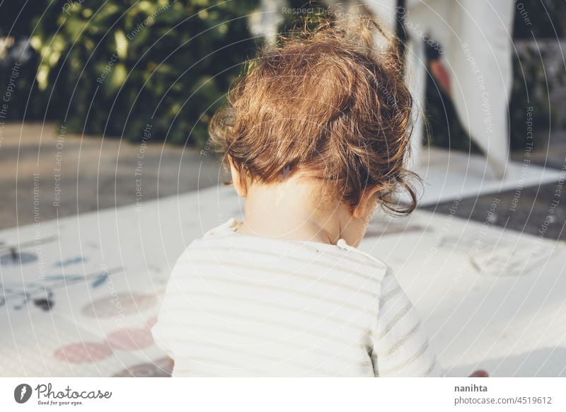 Rückansicht eines in der Natur spielenden Babys Säuglingsalter Kleinkind Rücken Ansicht im Freien Park Kindergarten spielerisch Sitzen allein Familie