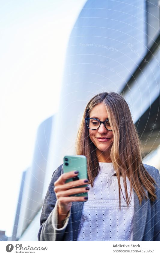 Frau, die beim Gehen auf dem Bürgersteig eine SMS auf ihrem Smartphone schreibt positiv benutzend Nachricht Straße formal Anschluss Internet Großstadt Arbeit