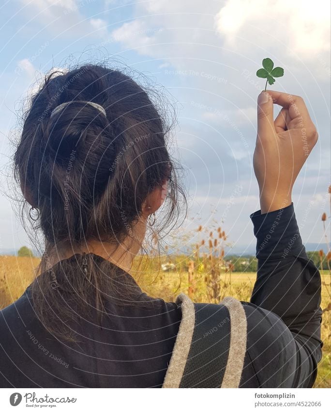 Glück - Frau hält ein vierblättriges Kleeblatt hoch Glücksklee Glücksbringer Wunsch selten glückliche Frau Natur Junge Frau Frisur hand symbolik Volksglaube