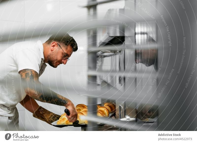 Männlicher Zuckerbäcker backt Kuchen in der Küche Mann Croissant geschmackvoll Gebäck lecker Lebensmittel Bäckerei selbstgemacht Tablett gebacken süß frisch