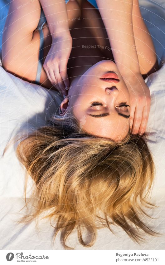 Schöne Frau auf dem Bett liegend. Frau hält die Augen geschlossen entspannt auf dem Bett trägt Bralette Top. schön Erholung bequem Porträt heimwärts