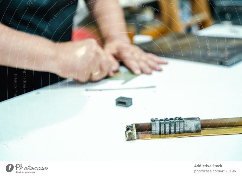 Anonymer männlicher Meister im Stehen und an der Werkbank im Druckatelier Mann messen Arbeit drucken Werkstatt Konzentration Werkzeug Hobelbank Kunstgewerbler