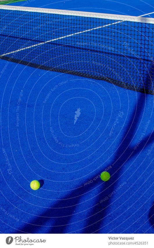 Zwei Bälle neben den Aufschlaglinien auf einem blauen Paddle-Tennisplatz. Schatten Padelplatz Gerichte Padel-Tennis Textur Boden Stillleben Rasen Kunstrasen