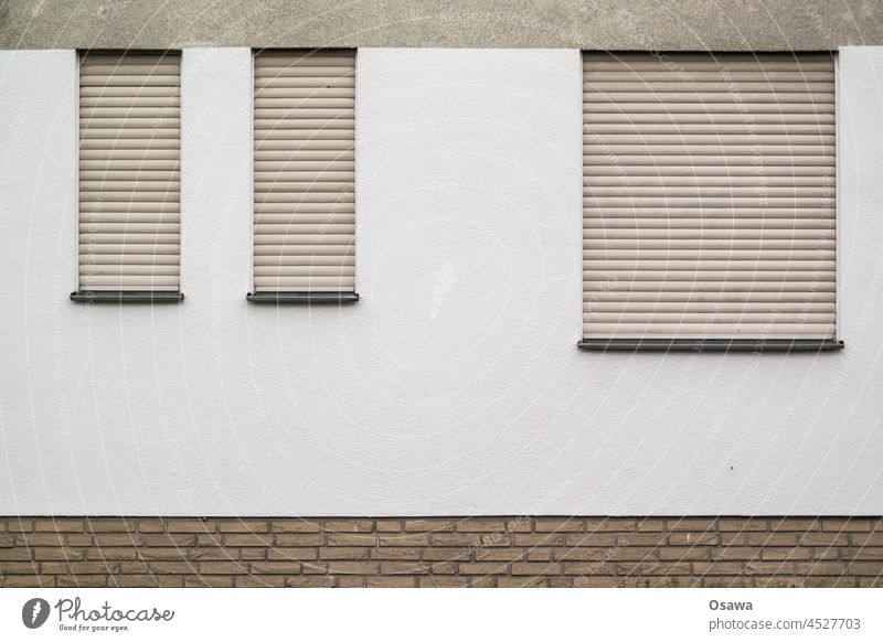 Drei Fenster mit geschlossenen Jalousien Fassade Wand 3 verschlossen beige Putz Mauerwerk grafisch Rechteckig Muster abstrakt Gbäude Haus Architektur eintönig