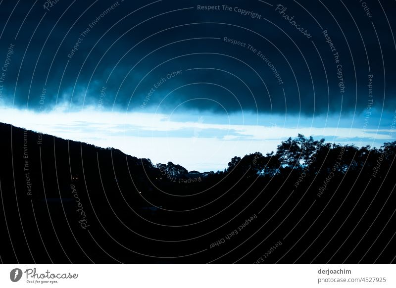 Eine dunkle Regenwolke schiebt sich über den noch hellen Horizont. Im Vordergrund die Hügel sind total abgedunkelt. Regenwolken Abend Wolken Himmel Sommer Natur