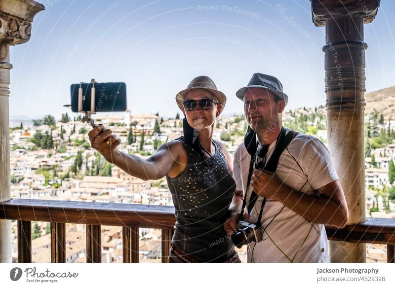 Ein Touristenpaar macht ein Selfie im Alhambra-Palast mit Blick auf Granada, Spanien nehmen Smartphone Erwachsener Architektur Fotokamera Kaukasier heiter