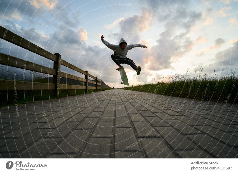 Aktiver Mann springt auf Longboard auf gepflastertem Weg springen Stunt Hobby Fähigkeit Freizeit Aktivität Freestyle cool männlich üben Trick Laufsteg