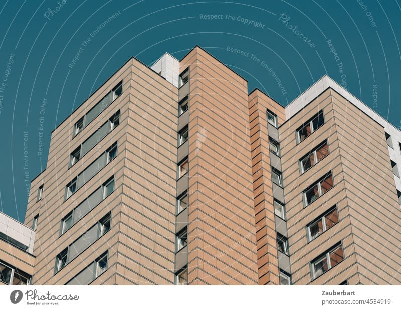 Fassade eines Mietshauses in beige-braun vor blauem Himmel Wohnhaus Hochhaus Großstadt Wohnen Stadt Wohnungen Wohnungsnot Mehrfamilienhaus zackig gezackt hoch