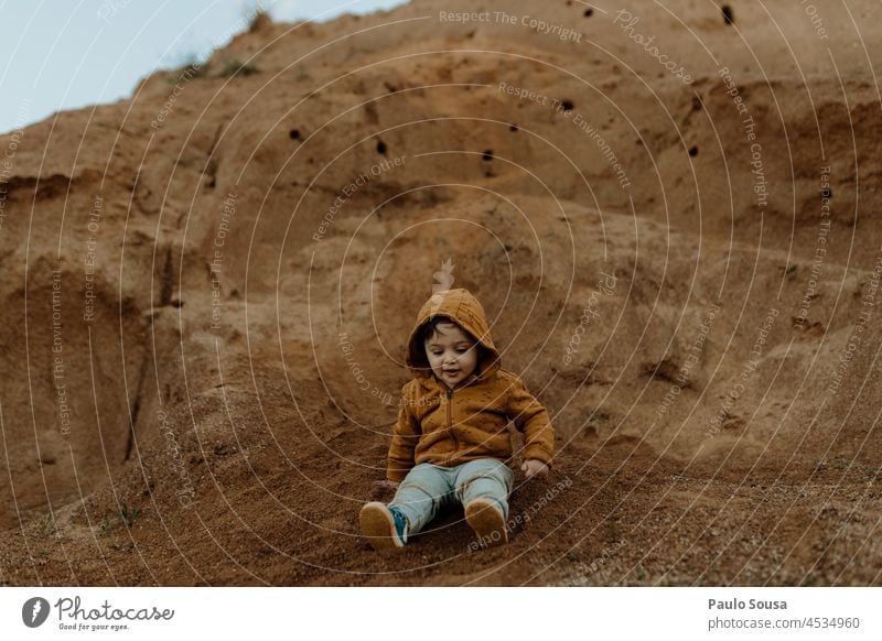 Kind spielt im Freien Kindheit 1-3 Jahre Junge Kindheitserinnerung Tag Außenaufnahme Farbfoto Freude Mensch erkunden Umwelt orange Kapuze Kapuzenpulli Herbst