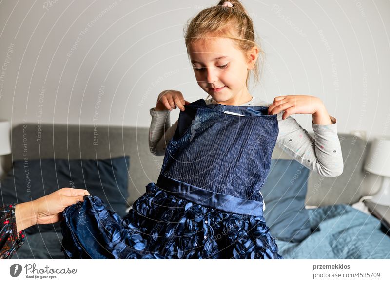 Mutter und ihre Tochter öffnen die Schachtel mit dem bestellten Kleid. Online-Shopper Kunde hält Kleid online kaufen Auspacken Orden Geschenk präsentieren