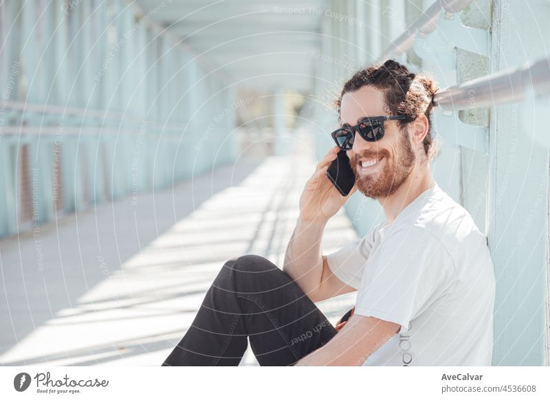 Junge Hipster-Mann auf dem Flughafen oder Busbahnhof warten, während ruft jemand mit dem Telefon, Gepäck, Taschen und Koffer. Lächelnde Hipster Reisende mit Sonnenbrille, Kopie Raum, sonnigen Tag